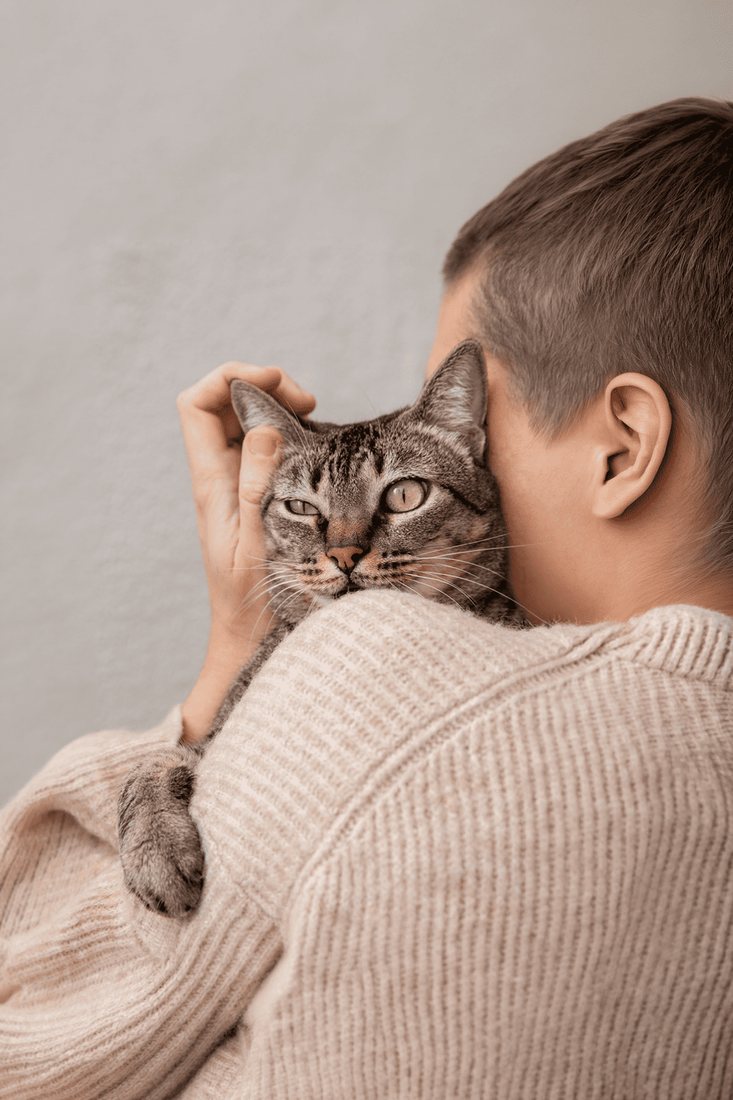 Tutor abrazando a su gato — el aceite de salmón también beneficia a los gatos